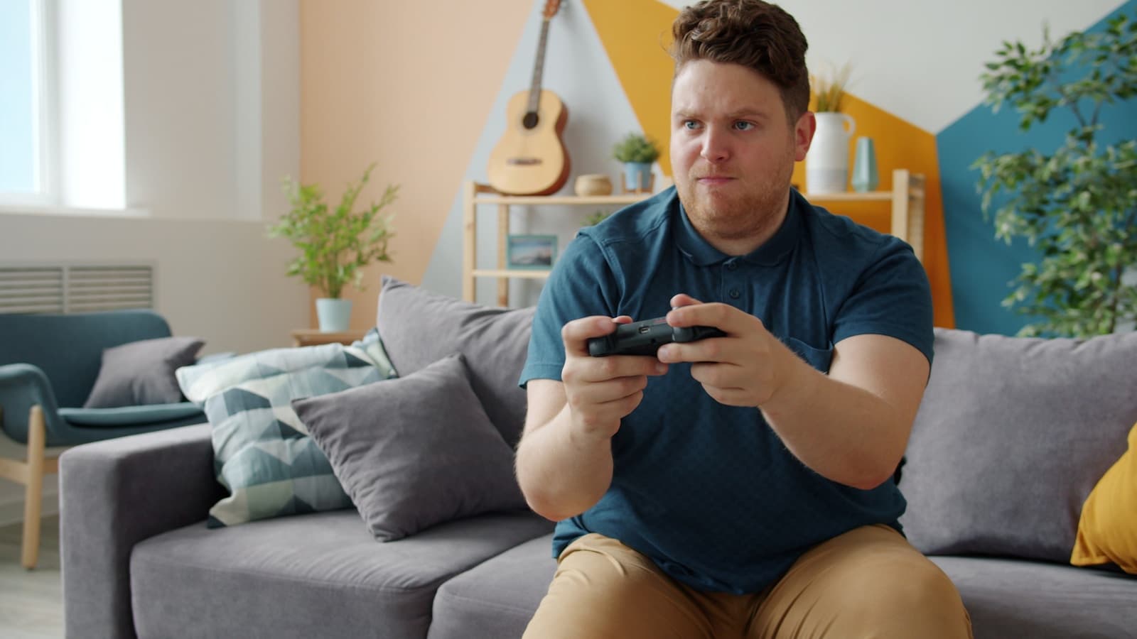 Person playing video games with a controller on a couch, representing a living-room Steam Controller setup